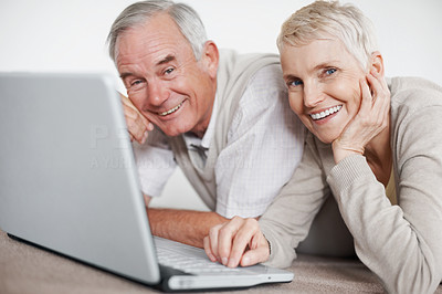 Older couple using a laptop while lying on the floor