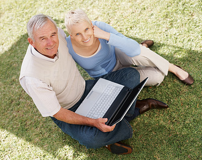 Top view of a senior couple using laptop on grass