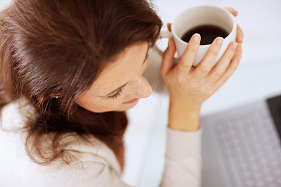 Top view of a woman holding coffee cup while using laptop