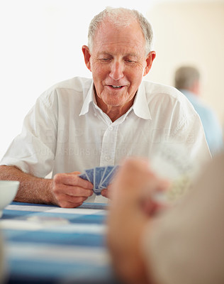 Happy retired man playing a game of cards