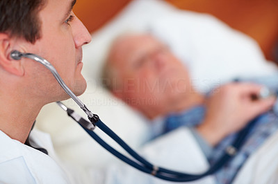 Doctor examining a senior man\'s heart beat with a stethoscope