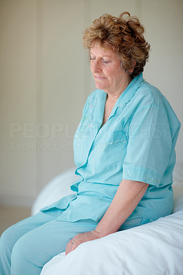Old woman sitting on a bed , sad feeling