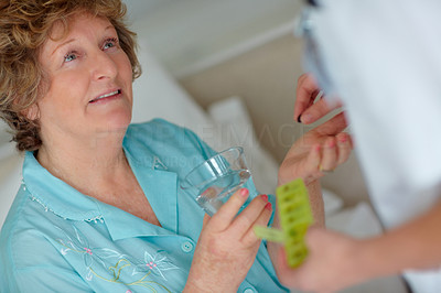 Senior woman being given a pill by doctor