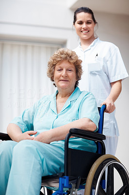 Elderly woman on a wheelchair being assisted by a nurse