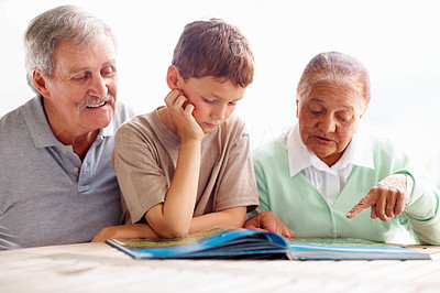 Small boy going through a book with grandparents