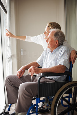 Old man on a wheelchair , nurse pointing outside