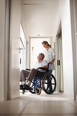 Nurse with patient on wheel chair at hospital corridor