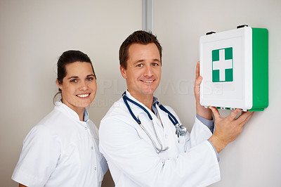 Happy doctors with a first aid kit up on the wall at hospital