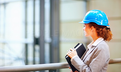 Young female wearing a hardhat with a folder in her hand looking away