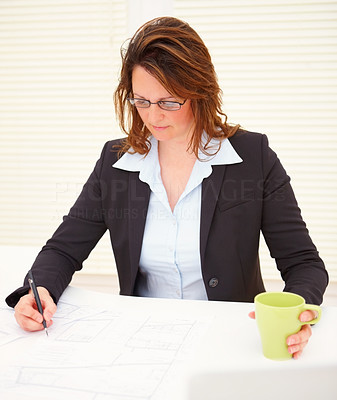 Business woman working on blue prints in the office