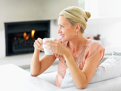 Happy mature woman having a cup of coffee , looking away