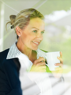 Business woman drinking coffee while looking outside window