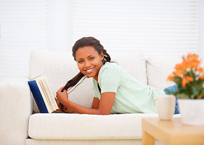 Young woman reading a book, resting on sofa