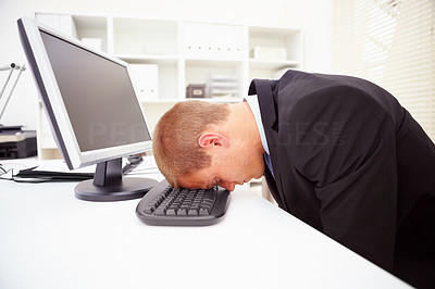 A tired businessman with his forehead resting on the keyboard
