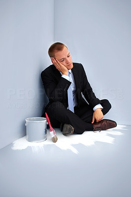 Tired young guy after painting a room, sitting in the corner