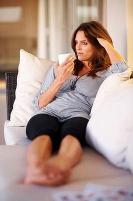 An attractive young lady relaxing on sofa with cup of coffee