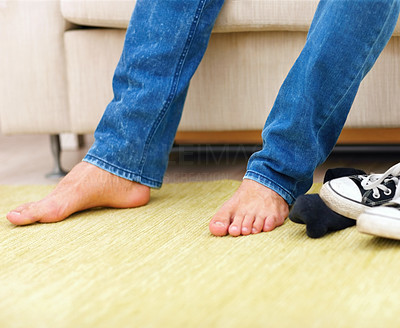 Man sitting on couch at home, focus on feet