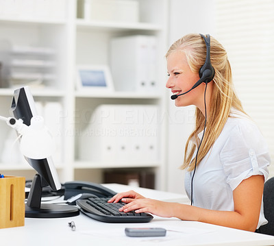 Cute young business woman working on computer, wearing headset