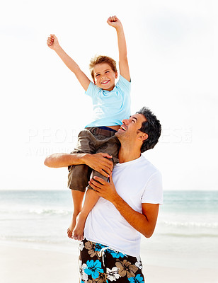 Handsome man carrying his son on the shoulder at the beach