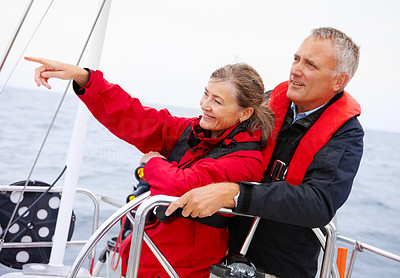 Mature couple on a sea voyage, pointing away