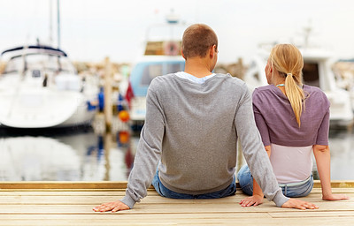 Rear view of a young couple seated on a footbridge, harbour view
