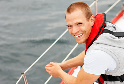 Happy young guy wearing a life jacket in a sail boat at sea