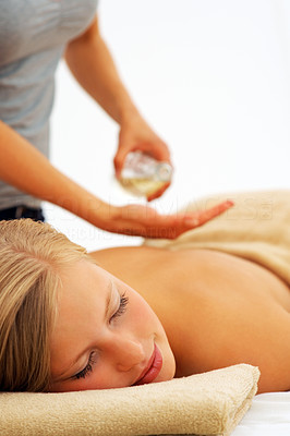 Young woman enjoying a back massage, masseuse using oil to massage