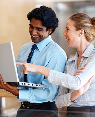 Business man holding a laptop, business woman pointing toward it