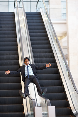Happy young business man playing at the escalator