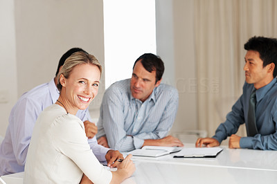 Business woman in board meeting with colleagues in background