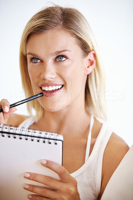 Thoughtful young woman writing on notepad
