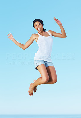 Happy young woman jumping in joy against sky