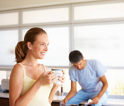 Woman having tea with husband in the background, home view