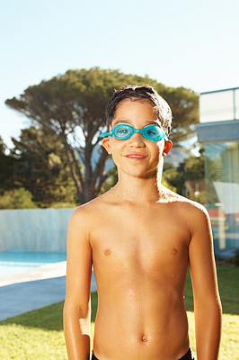Happy young boy wearing swimming goggles by the pool, outside