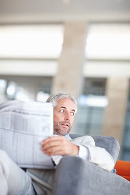 Mature business man looking away holding newspaper