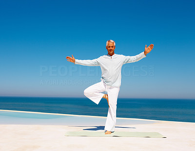 Full length image of a mature man practicing yoga at the sea shore