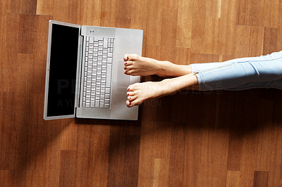Legs of a young woman lying on the floor with laptop