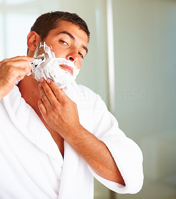 A young man shaving his beard