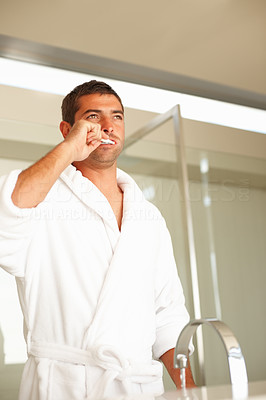 Man in a white bath robe brushing his teeth