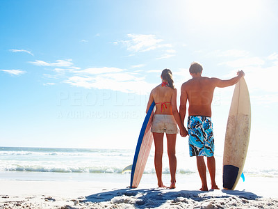 Happy couple with surf boards by the sea