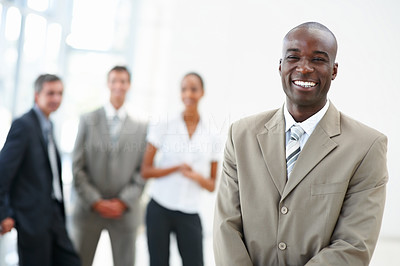 A satisfied African American business man with coworkers standing behind
