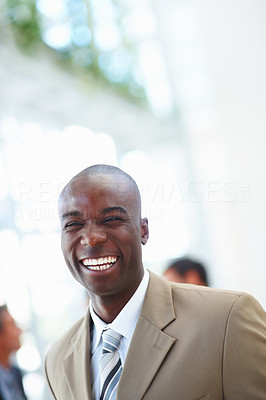 A laughing African American business man with people at the background