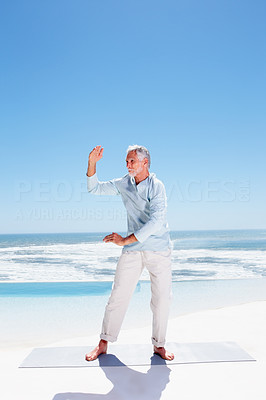 Senior man practicing martial arts on the beach
