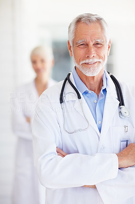 A confident senior doctor posing with hands folded