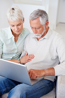 A senior retired couple working on a laptop