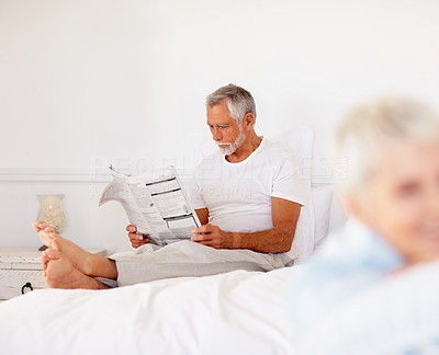 An old senior man reading a newspaper at home
