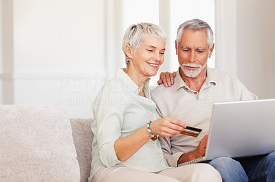 Cute elderly couple at home shopping with their credit card from the net