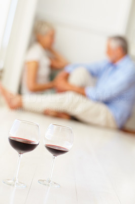 Closeup of wine glasses on the floor with an couple at the background