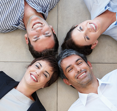 A happy business group lying in a circle on the floor