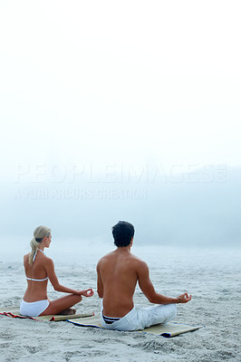 Young couple sitting at the beach in lotus position